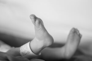 Close-up of a newborn baby's feet with an ID bracelet, symbolizing new life.